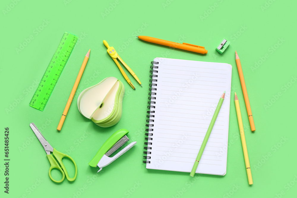 Colorful pencils with stationery on green background