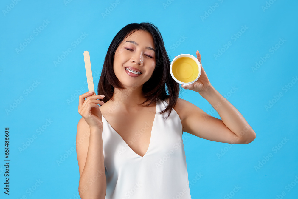 Young Asian woman with wax on blue background