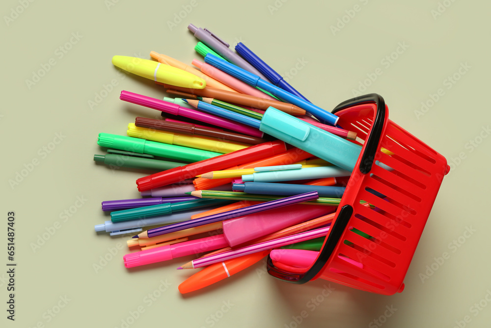 Shopping basket with different school stationery on light background