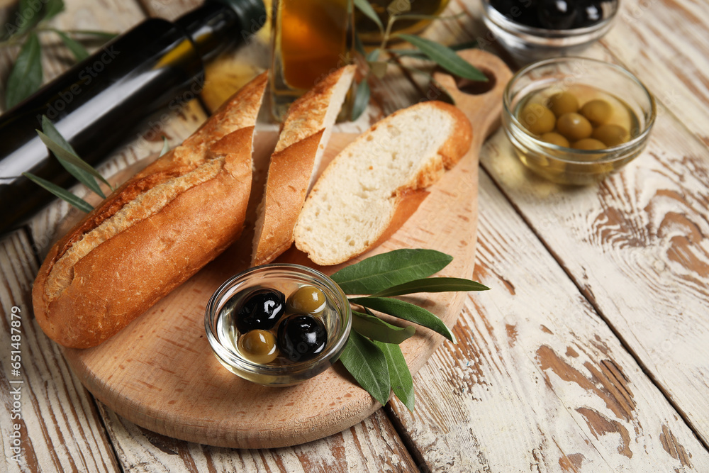 Board with fresh olive oil and bread on white wooden background