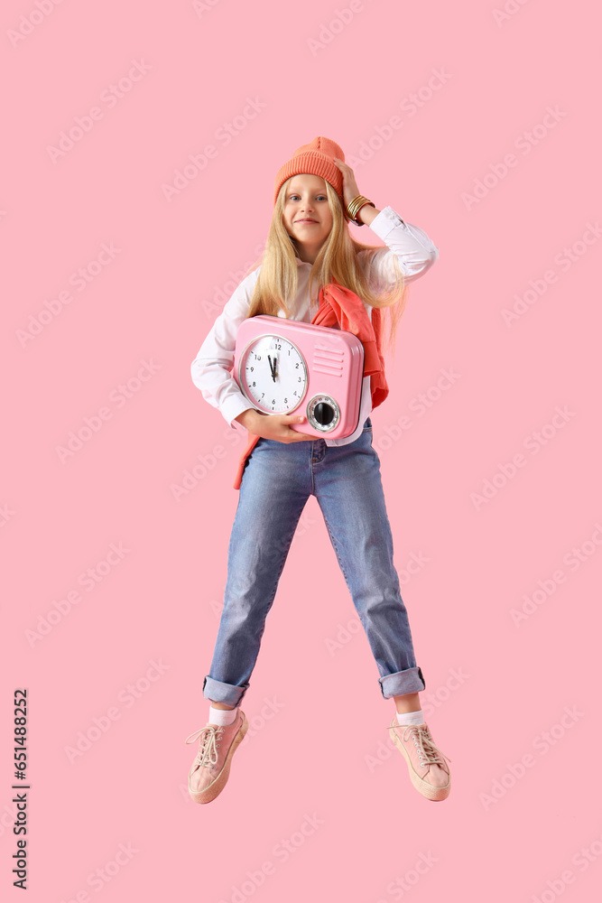 Jumping little girl with clock on pink background