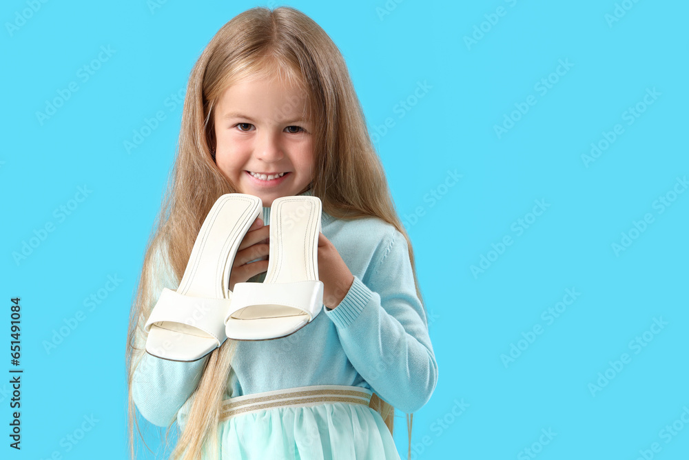 Cute little girl with heels on blue background