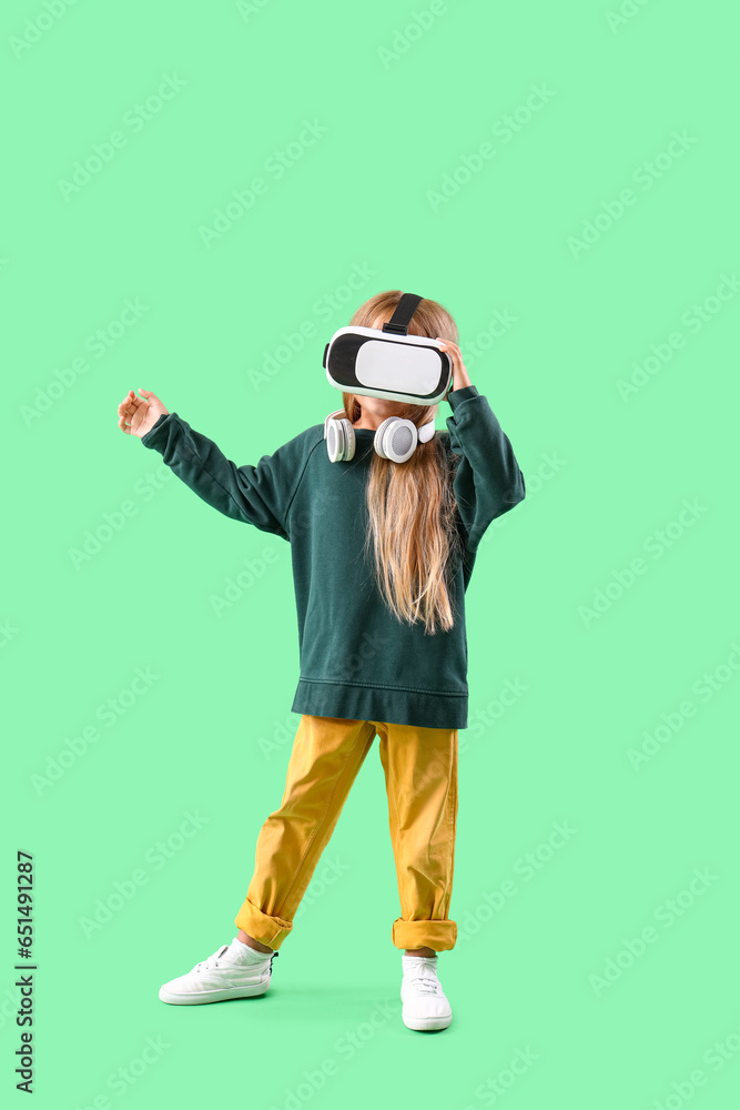 Cute little girl in VR glasses on green background