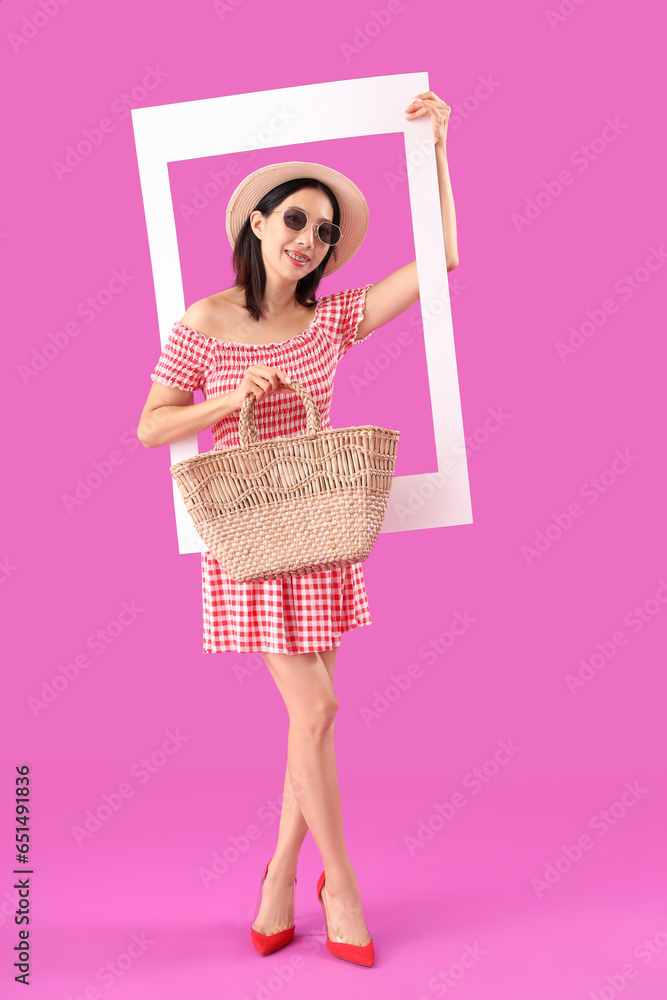 Stylish young beautiful Asian woman with frame on purple background