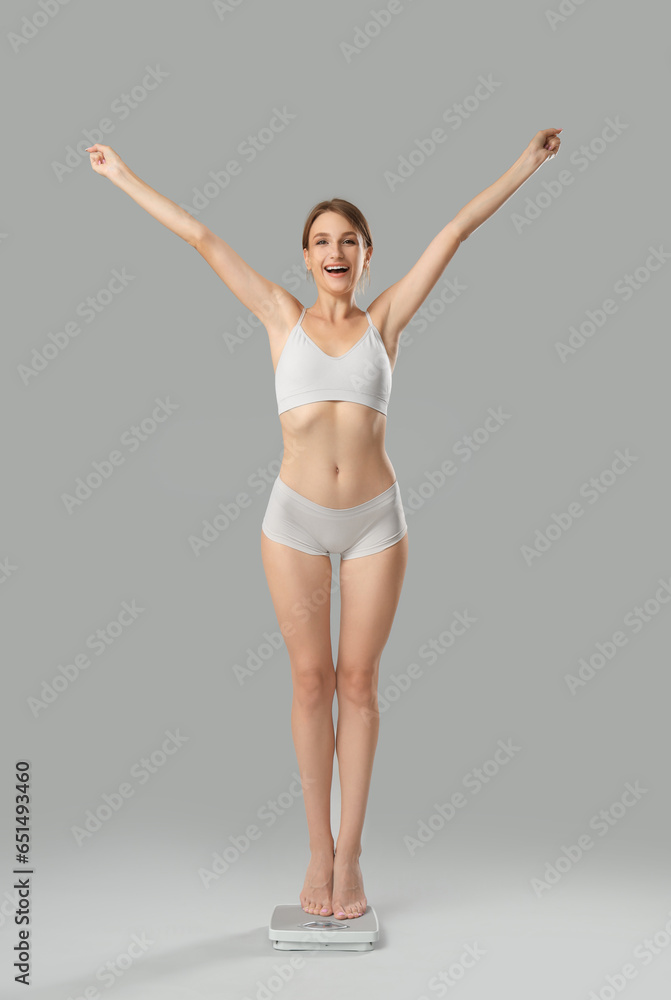 Happy young woman with scales on grey background. Weight loss concept