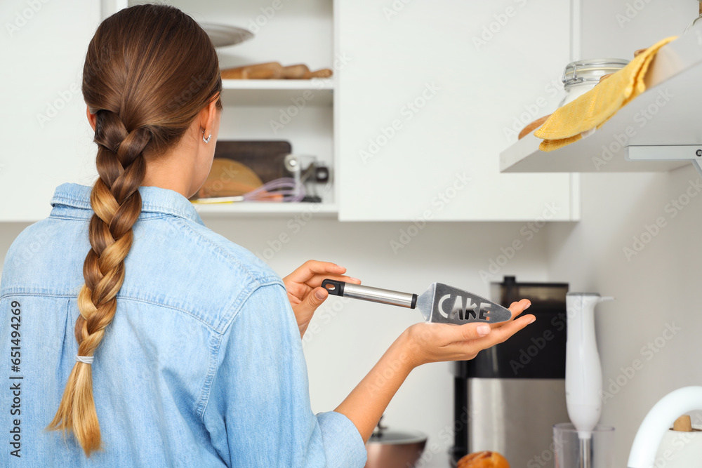 Woman putting spatula into kitchen cupboard