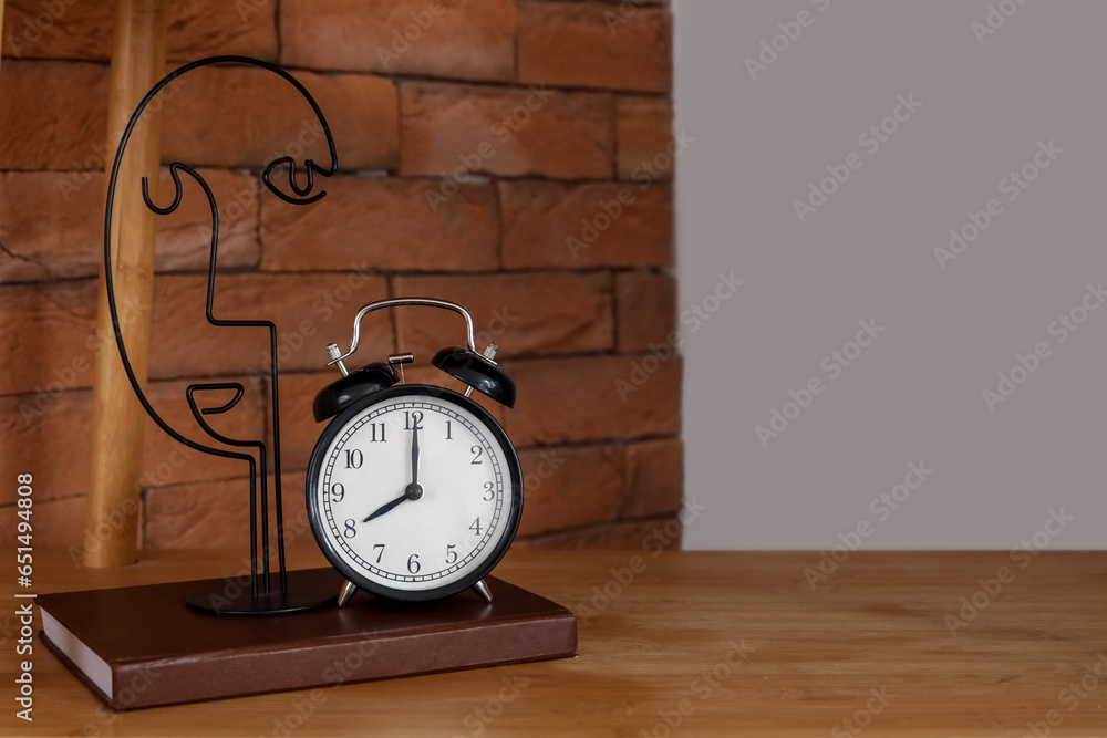 Alarm clock and decor on wooden table in bedroom, closeup