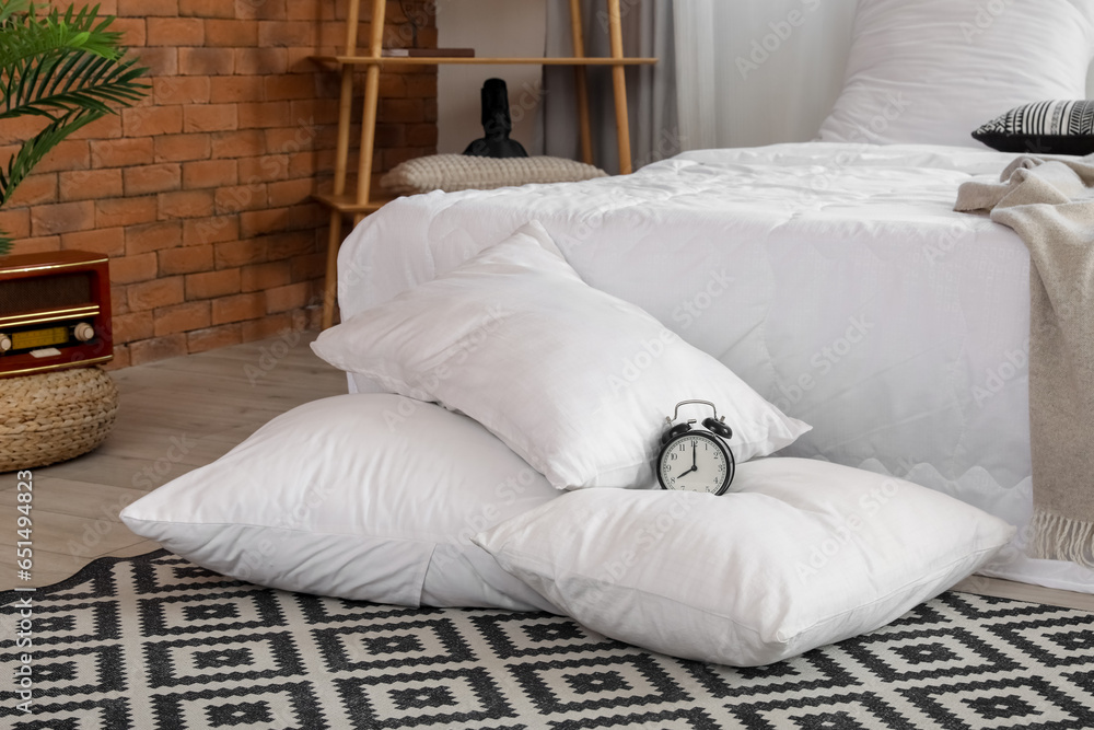 Alarm clock on white pillows in bedroom