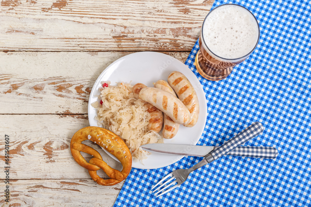 Plate with tasty Bavarian sausages, pretzel, sauerkraut and glass of beer on white wooden background. Oktoberfest celebration