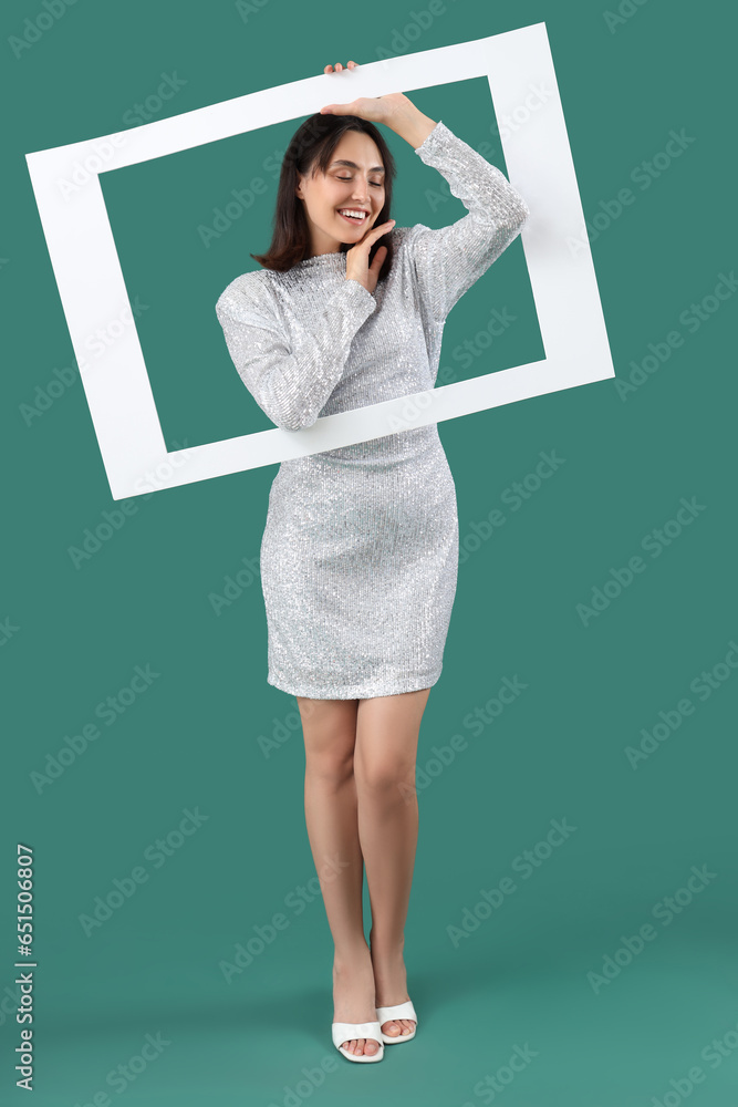 Beautiful young woman with frame on green background