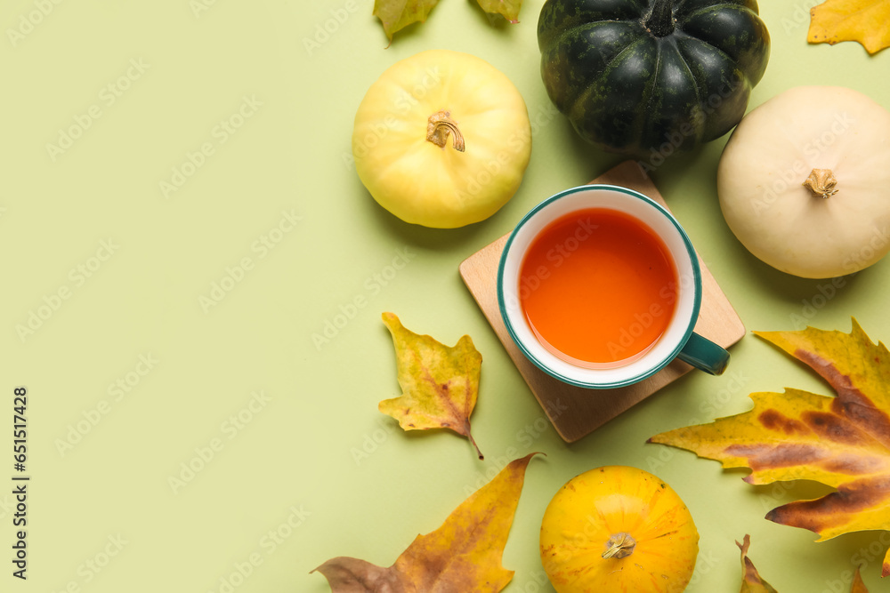 Composition with cup of tea, ripe pumpkins and autumn leaves on color background