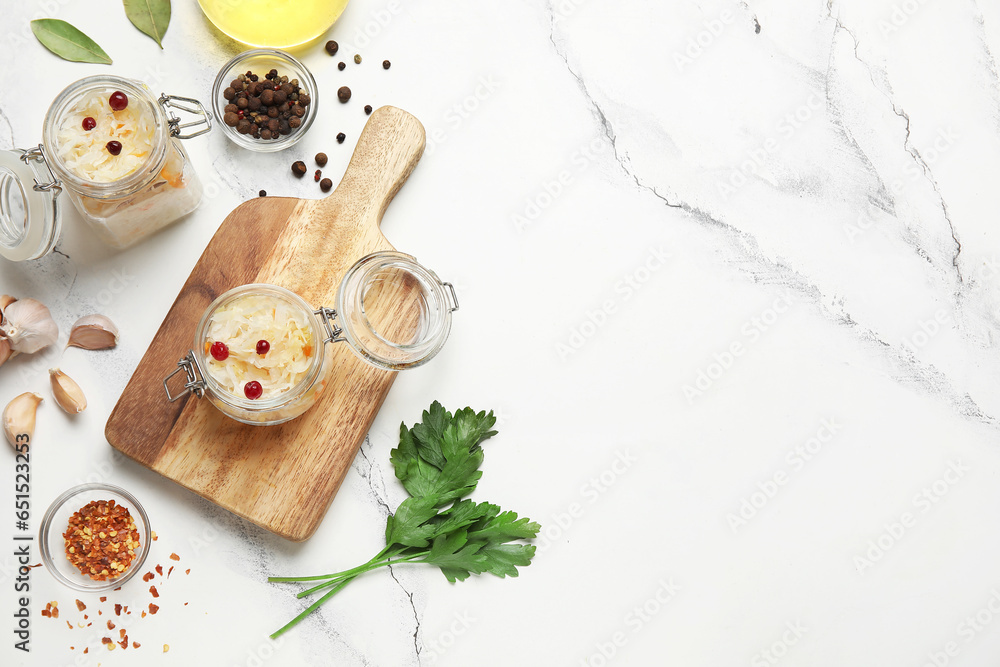 Jars with delicious sauerkraut and different spices on white background