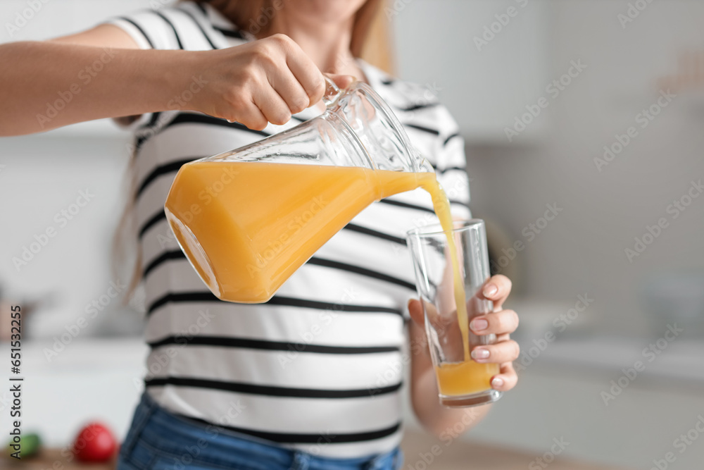 Young pregnant woman pouring juice into glass in kitchen, closeup