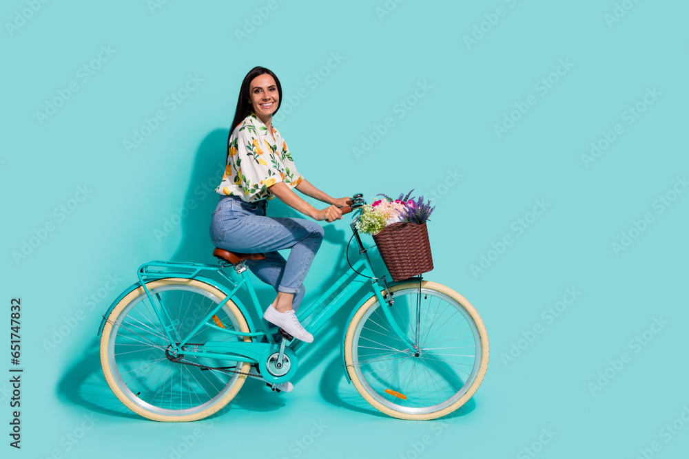 Full length photo of lovely pretty girl wear stylish outfit having fun riding bicycle empty space isolated on bright cyan color background