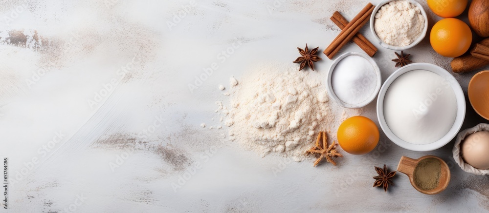 Flat lay baking background with flour eggs sugar spices and whisk on a white tabletop