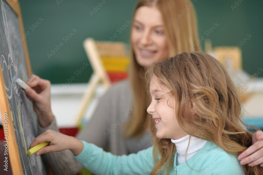 Mother and daughter drawing pictures on wooden board