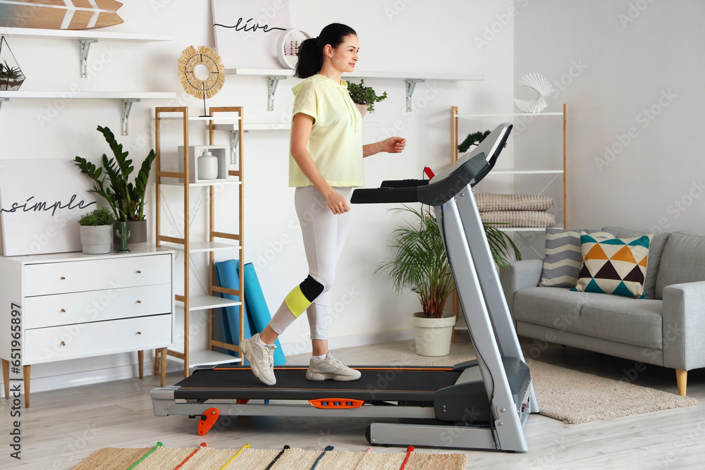 Beautiful woman training on treadmill at home