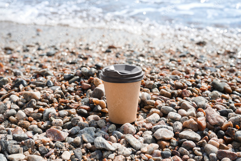 Takeaway cup of hot coffee on beach