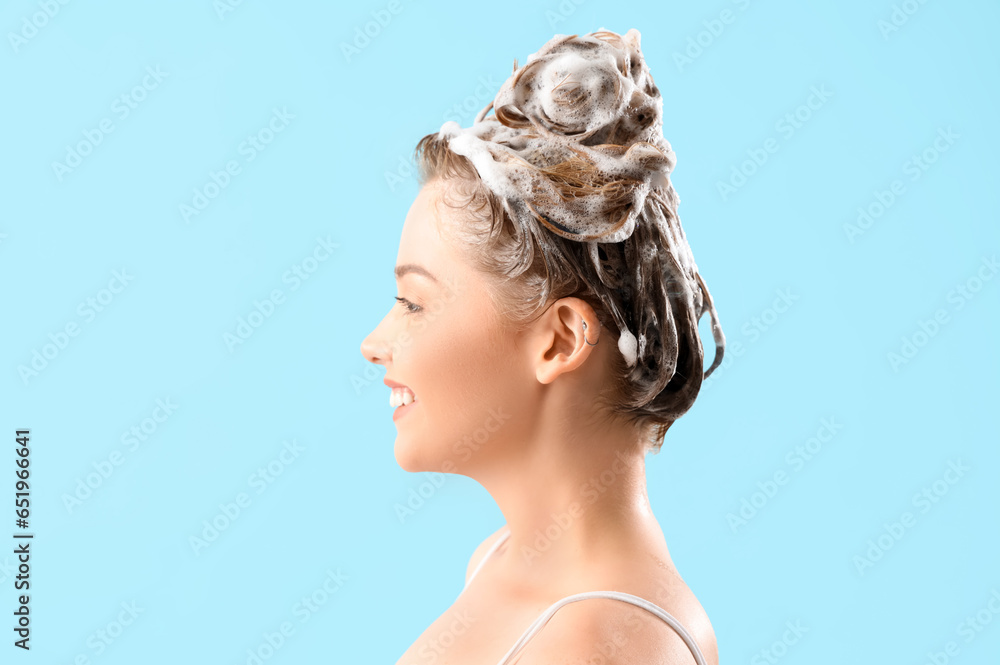 Young woman with shampoo on blue background, closeup