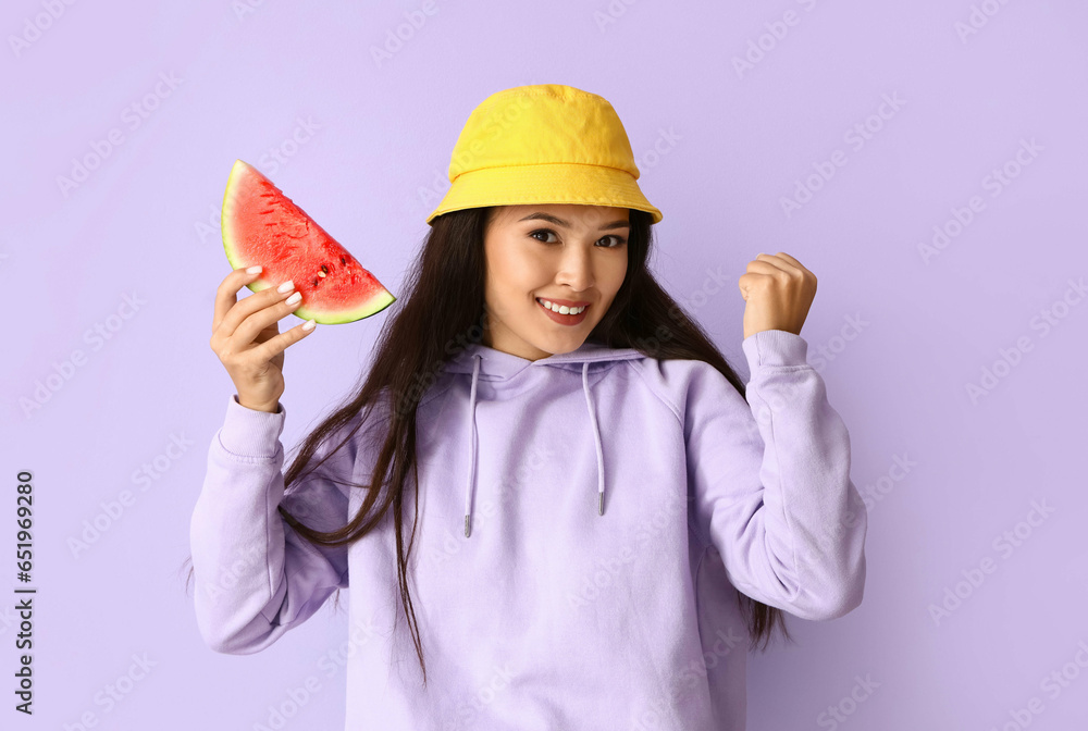 Beautiful young Asian woman with slice of fresh watermelon on lilac background