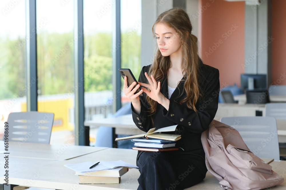 Portrait of a schoolgirl at school. She holds books in her hands. Education concept.