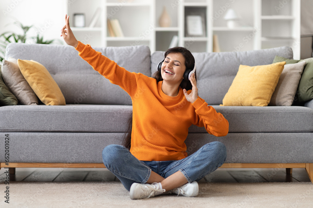 Positive millennial indian woman listening to music at home