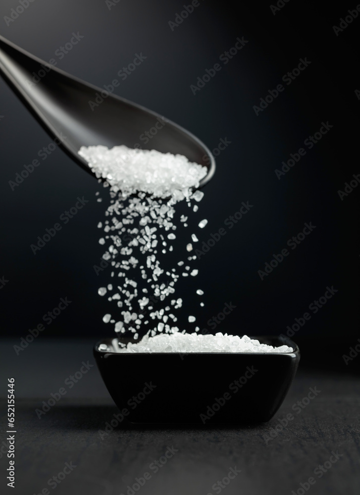 Sea salt is poured into a black bowl.