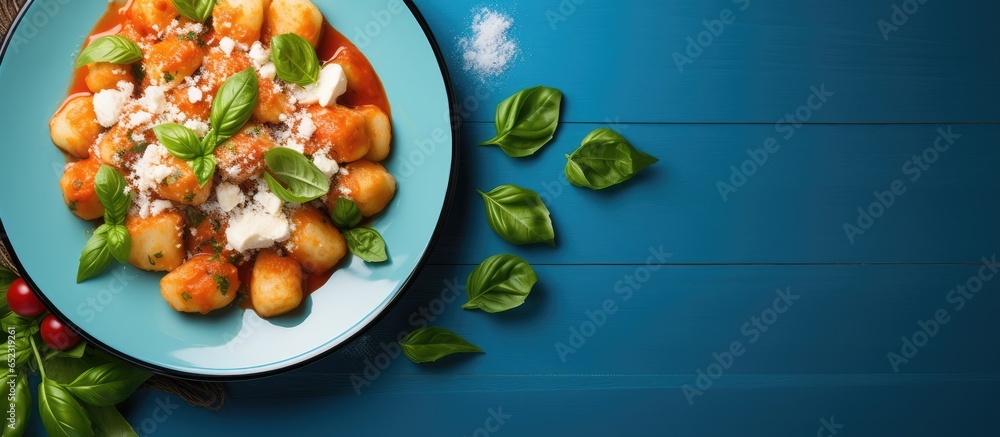 Top view of Italian gnocchi with tomato sauce parmesan fresh basil on blue backdrop