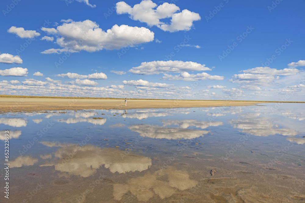 Scenic sunlight landscape, shore of salt lake, water surface and reflections sky with clouds. Mirror reflex on water. Beautiful aesthetic nature view. Ulzhay (Uldjay) lake in Omsk region