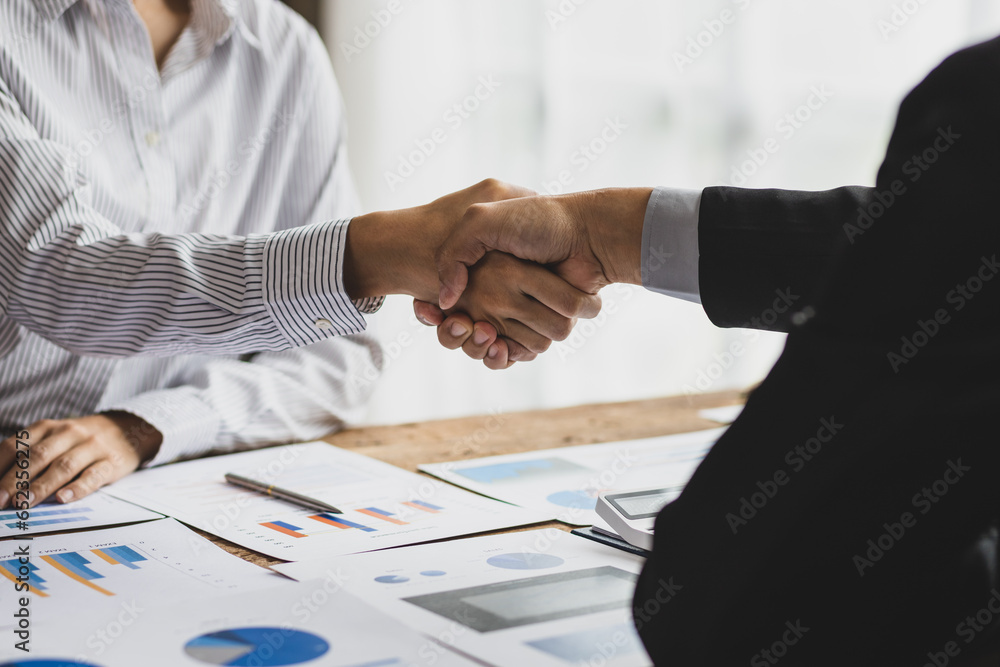 Businesswoman shaking hands with financial advisor at meeting in office.