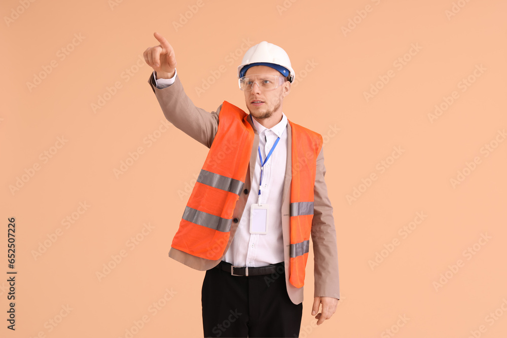 Male architect in vest pointing at something on beige background