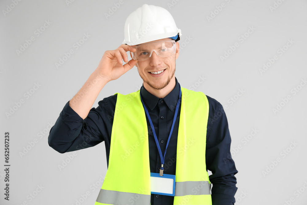 Male worker in vest and hardhat on grey background