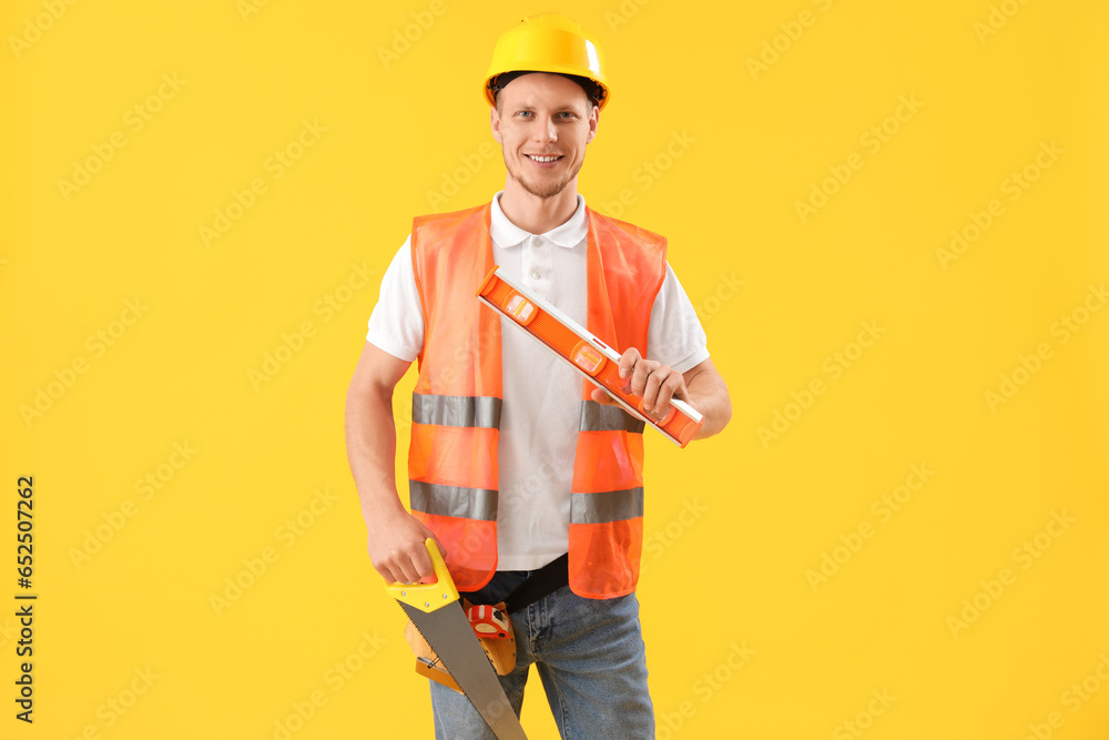 Male worker with builders level on yellow background