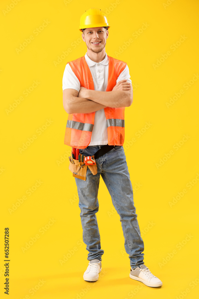 Male worker in vest on yellow background