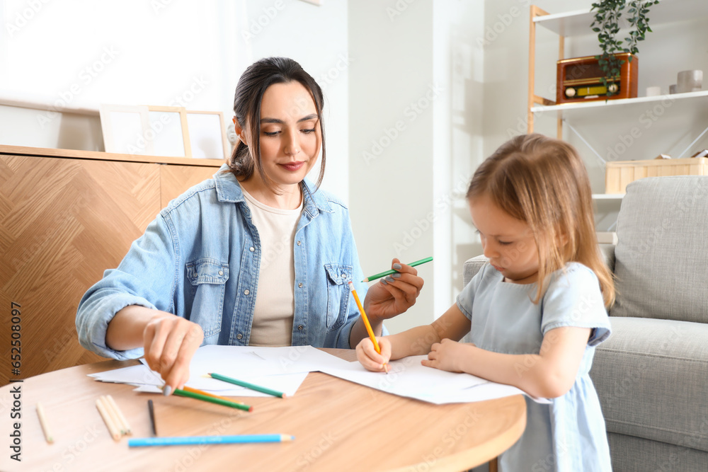 Young woman with her little daughter drawing at home