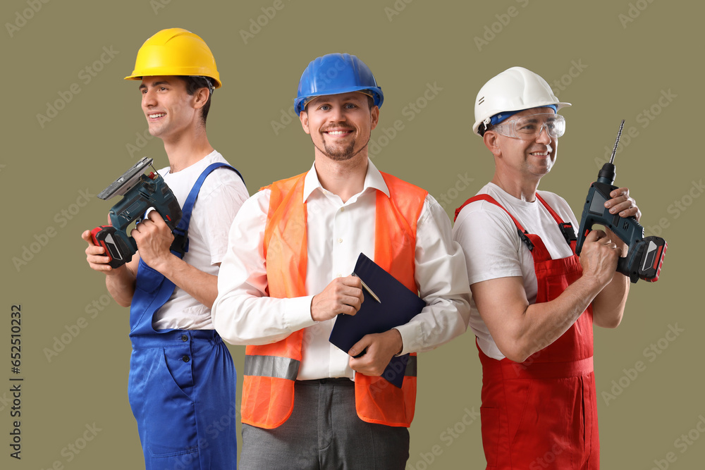 Team of male builders with tools on green background