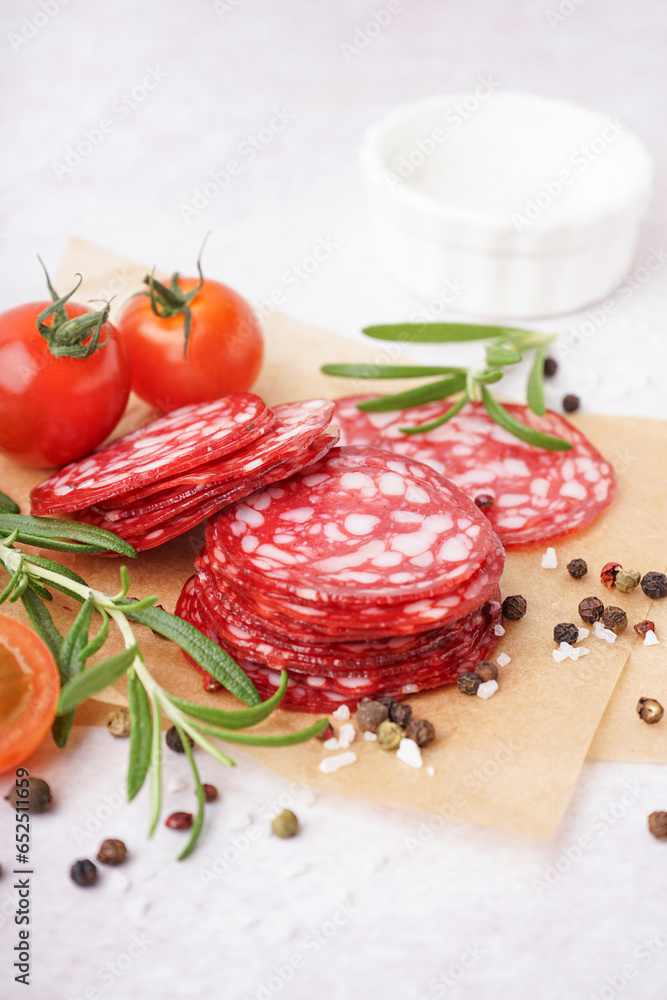 Slices of tasty salami on light background