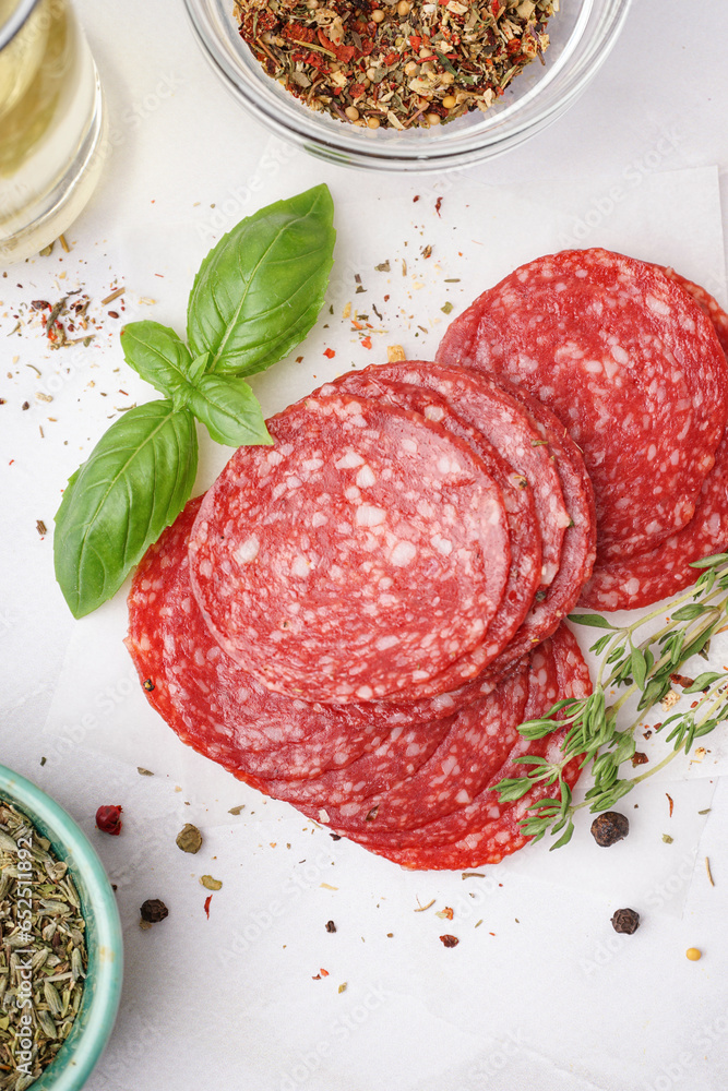 Slices of tasty salami on light background