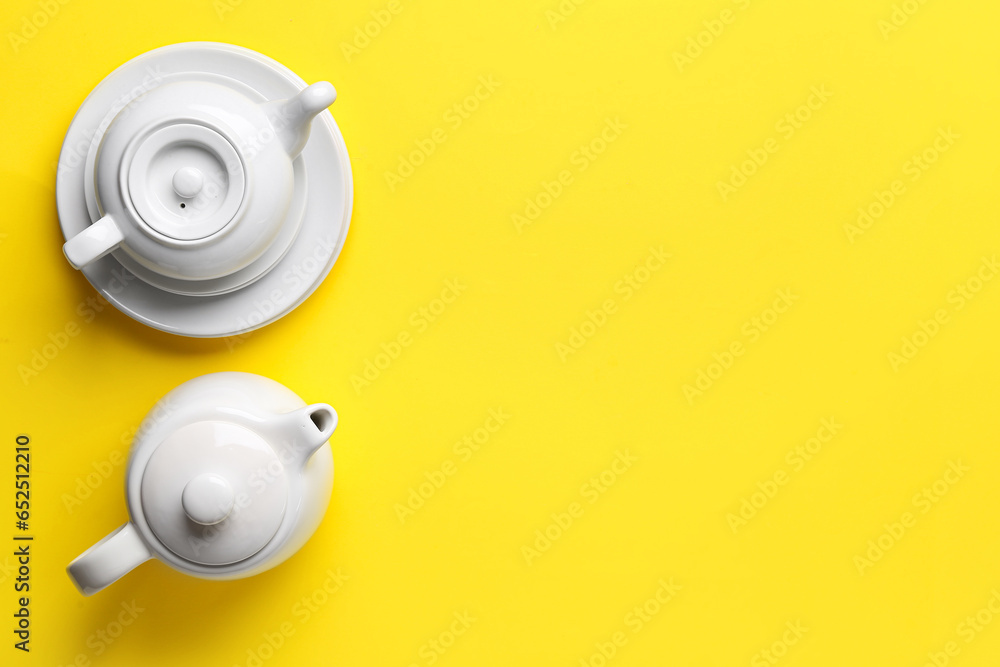 Teapots and plates on yellow background