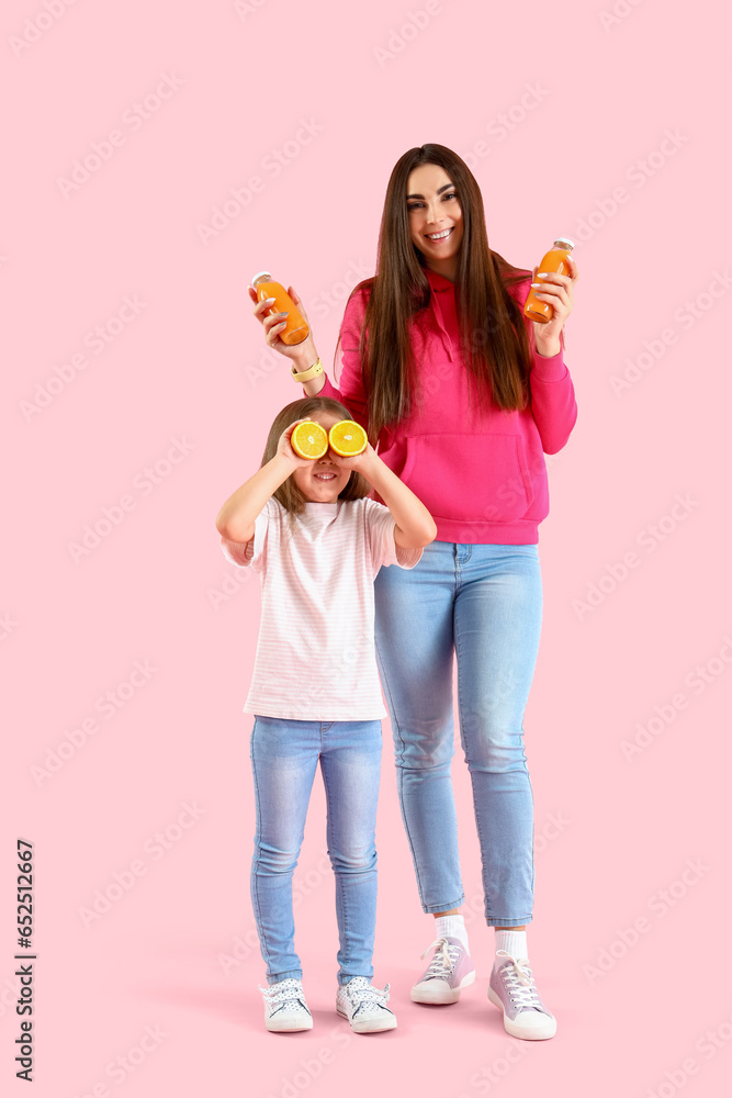 Little girl with her mother and orange juice on pink background