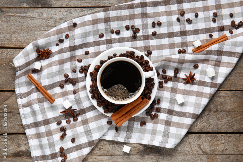 Cup of tasty coffee with cinnamon and beans on wooden background