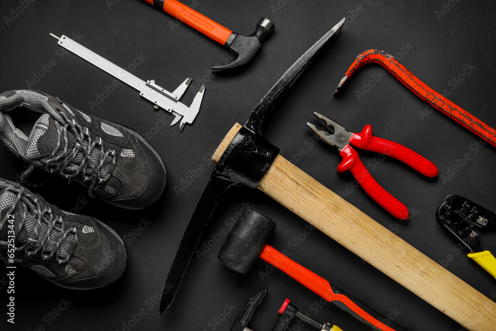 Set of construction tools and shoes on black background