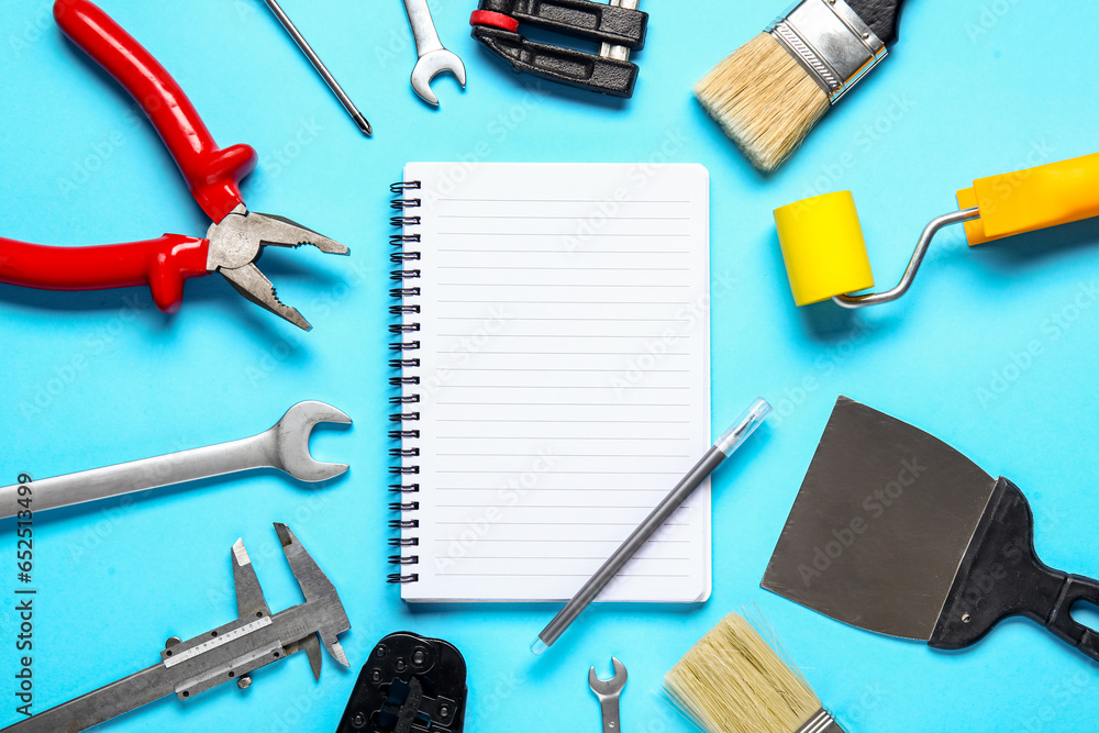 Set of construction tools, notebook and pen on blue background