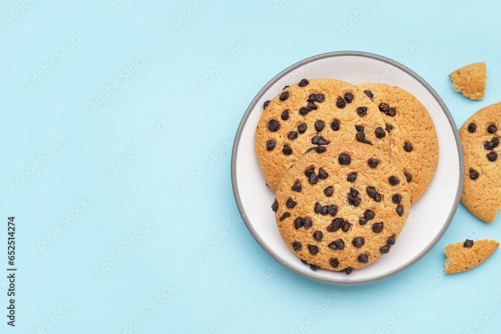 Plate of tasty cookies with chocolate chips on blue background