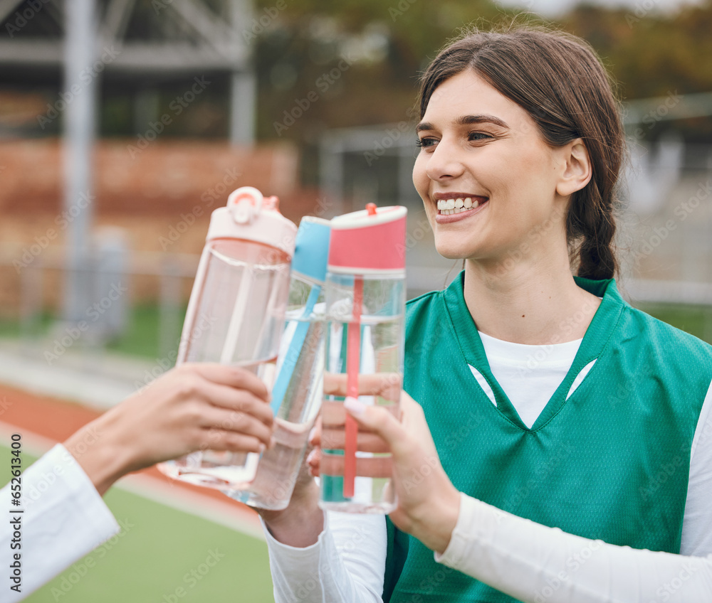 Cheers, water bottle and woman with hockey team on break together at sports training, match or competition. Smile, celebrate and people on a field for fitness or exercise in victory with teamwork