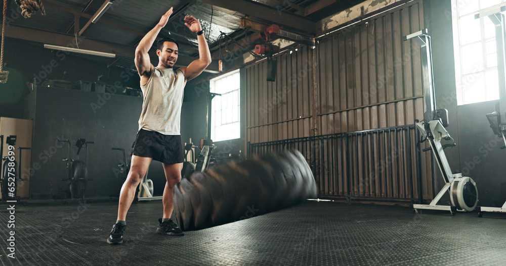 Gym, man and tire workout for strong muscle, power and action of sports challenge, energy and exercise. Asian bodybuilder, training and flip heavy tractor wheel for fitness, resilience or performance