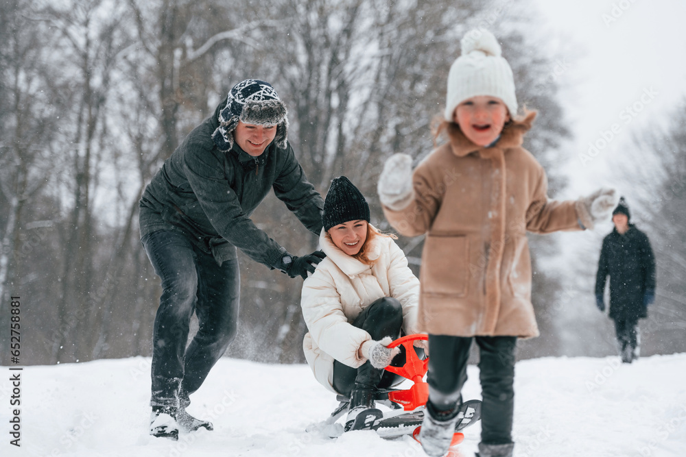 Woman is on sled ride. Happy family is outdoors, enjoying snow time at winter together