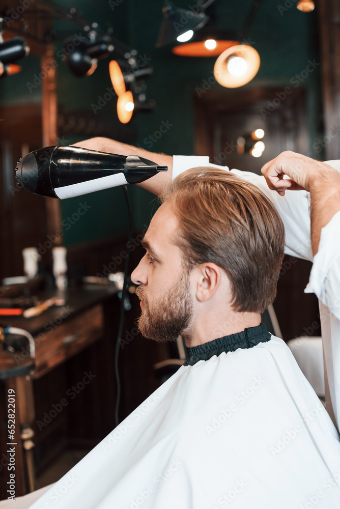 Using hair dryer. Man is visiting modern barber shop. Modern style