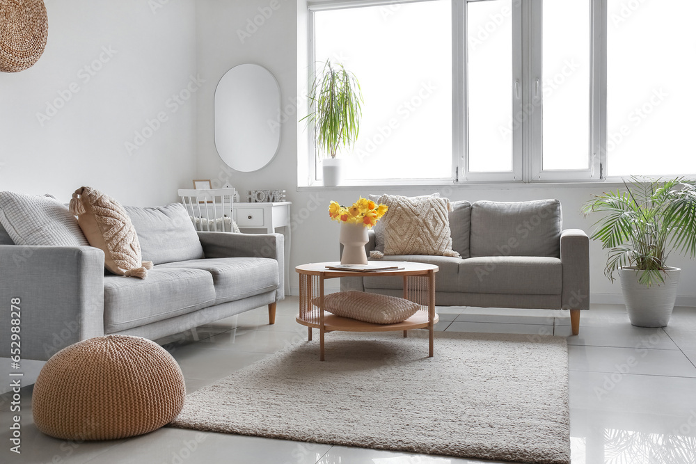 Interior of modern living room with cozy sofas and flower vase on coffee table