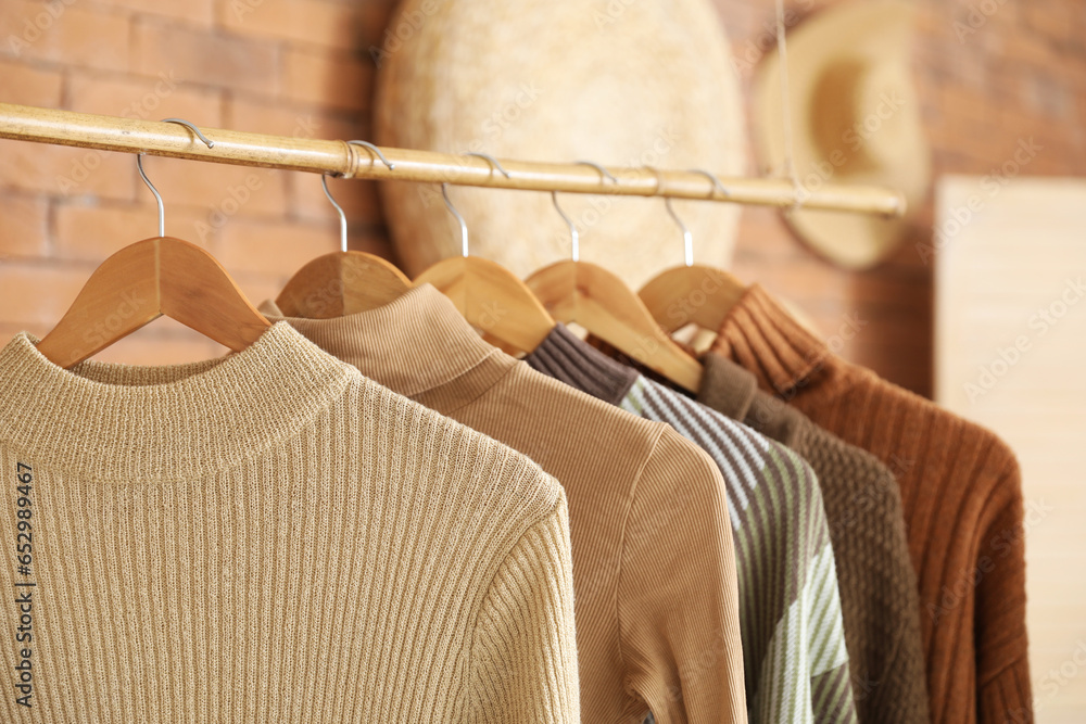 Rack with stylish female sweaters in boutique, closeup